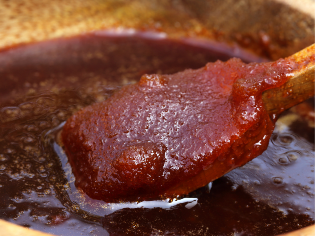 Thick, rich date paste being stirred with a wooden spoon in a bowl.