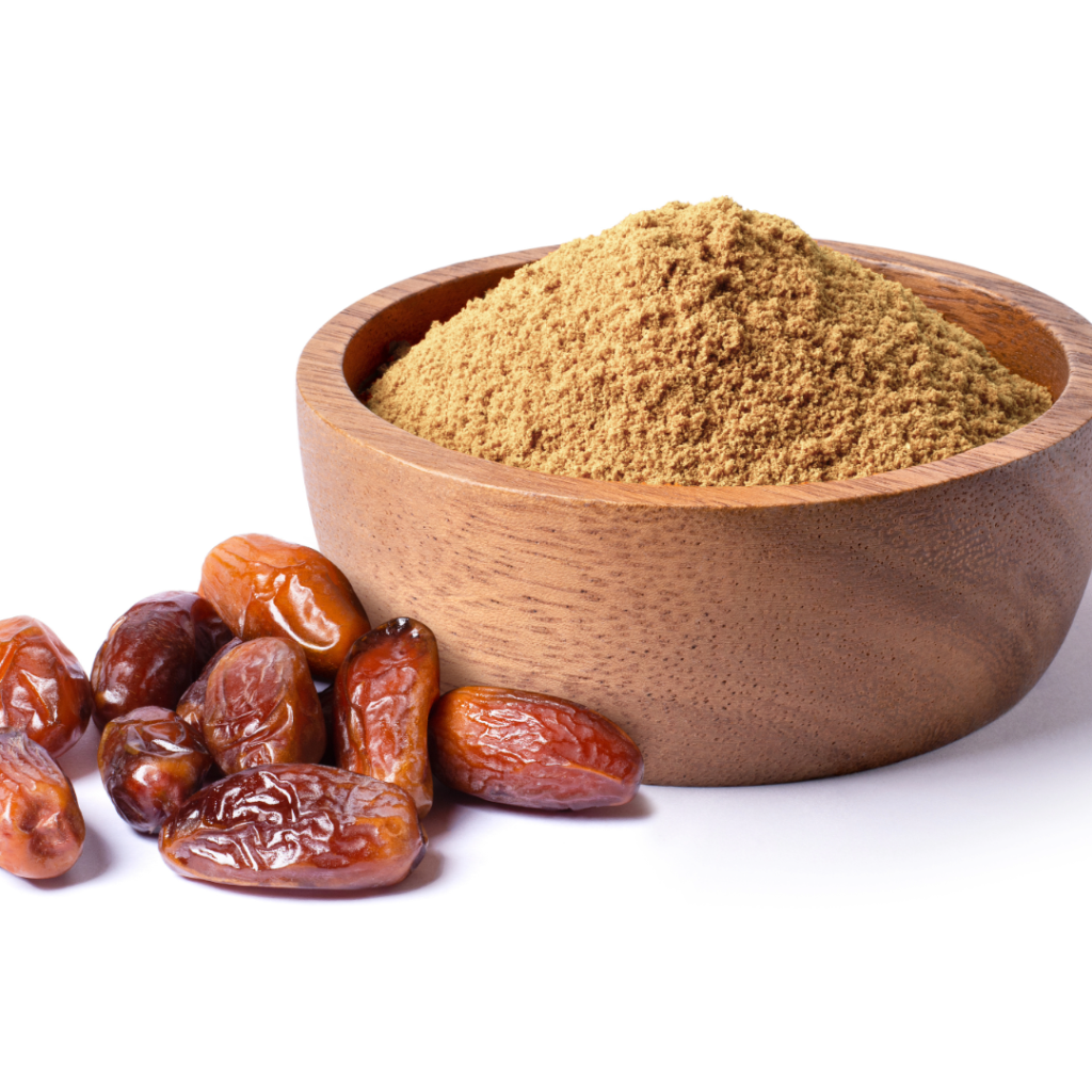 Close-up of whole dates next to a wooden bowl filled with finely ground date powder.